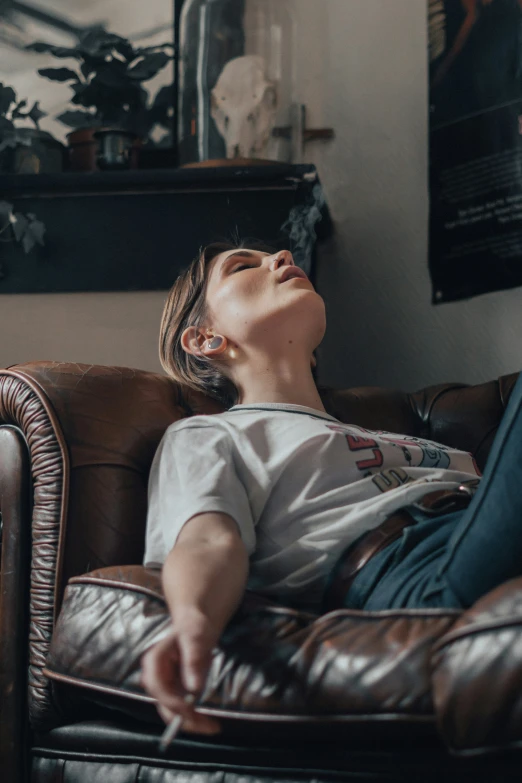 the man is sleeping on the leather chair while holding his hand to his stomach