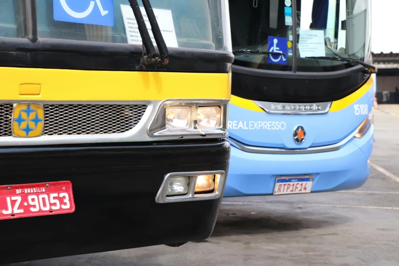 the front of a yellow and blue bus parked next to another