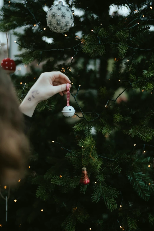 person hanging decorations on a christmas tree