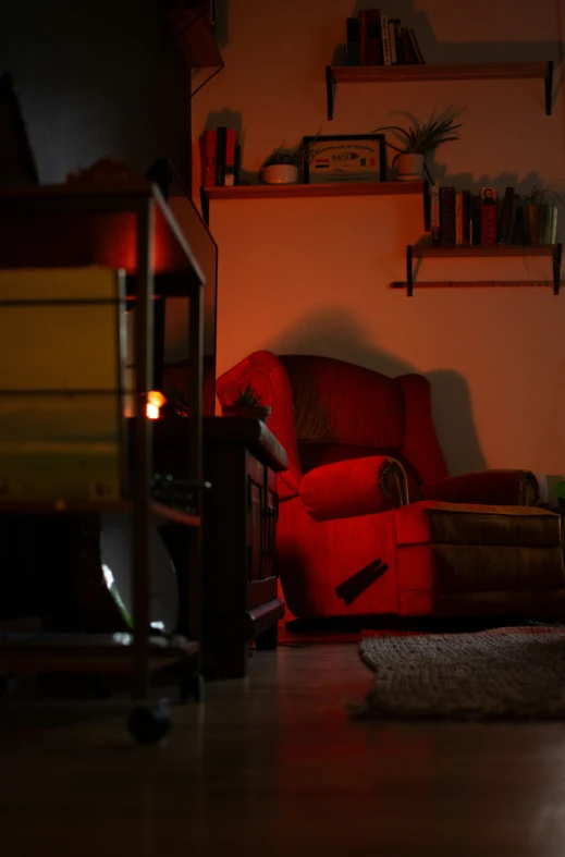 a red chair sitting in a dark room next to a wall