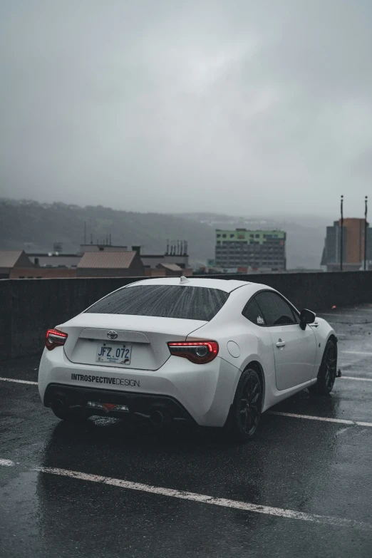 the rear end of a white sports car in the rain