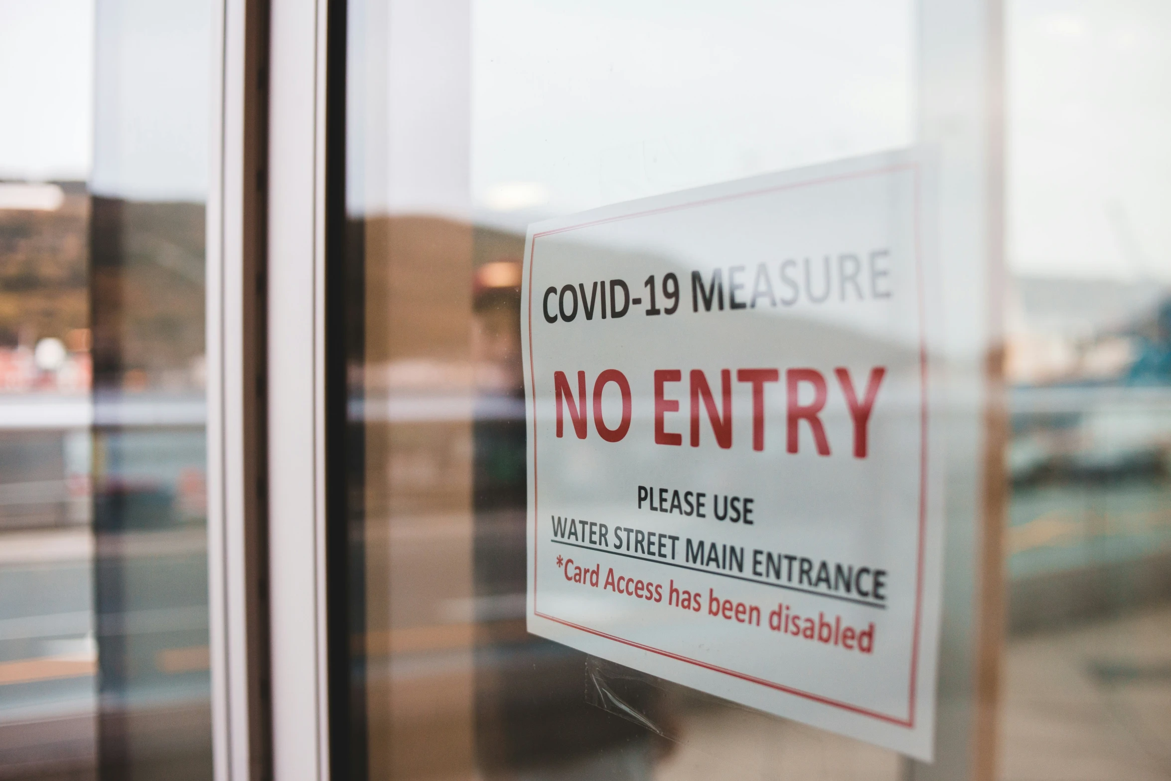 a sign that says no entry with the text covidd - 19 measure is posted on the glass