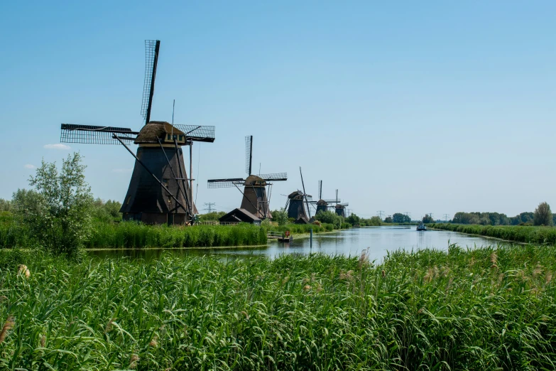 the three windmills are standing near a body of water