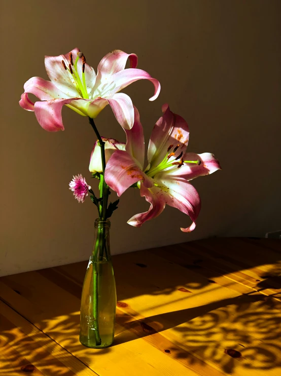 a vase with flowers sitting on a wood floor
