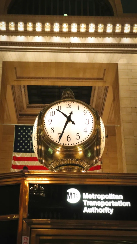 a clock hanging off the side of an entrance with american flag