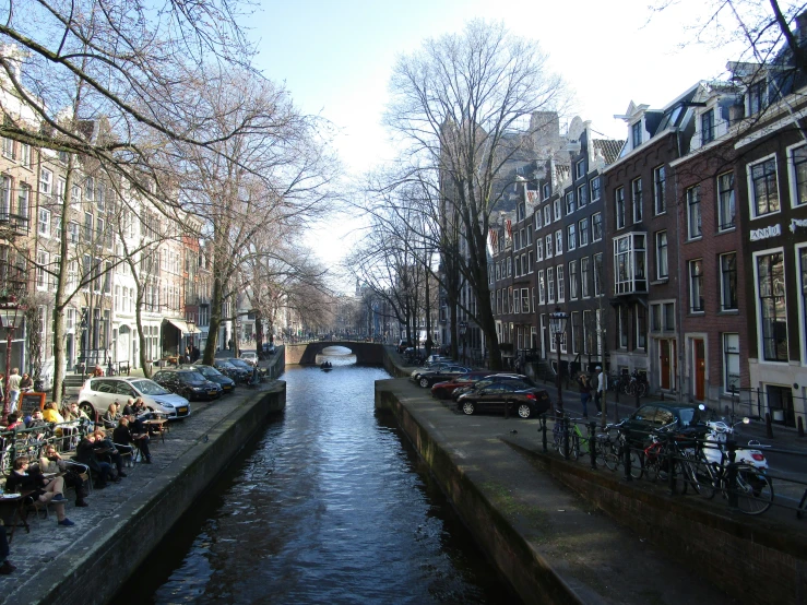 some people sit on the benches along a stream by the bikes