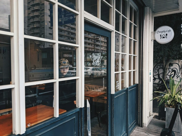 window on the side of a restaurant with a person in the reflection