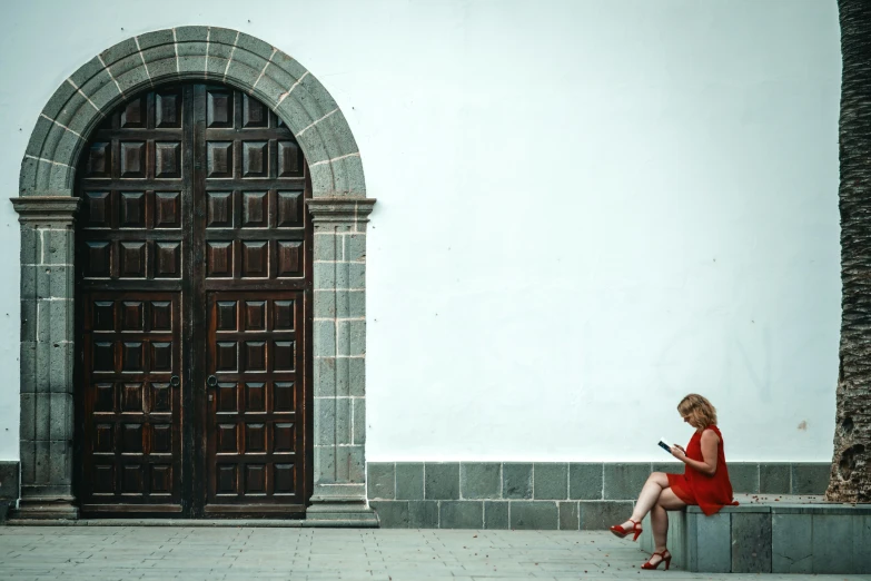 woman sitting on wall with open doors looking down