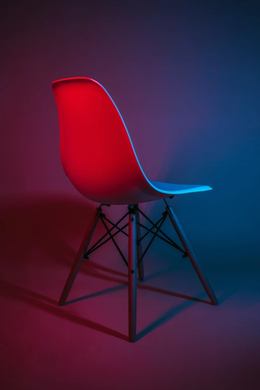 a blue, red and black plastic chair against a purple background