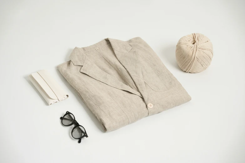 a pair of glasses, a jacket and hat are laying on a white surface