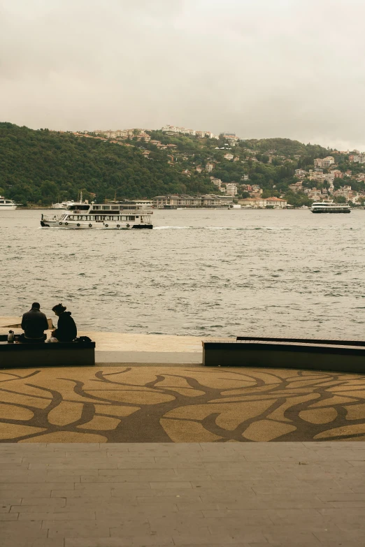 there is a couple on the bench that overlooks a lake