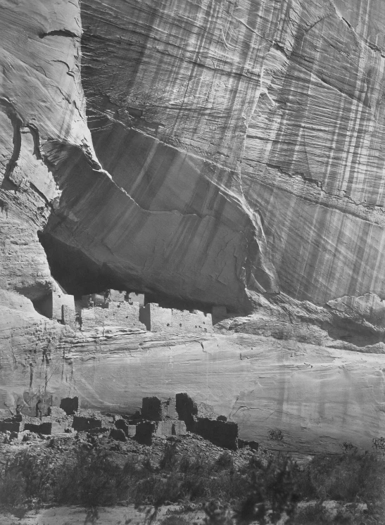 black and white pograph of the cliff side and an ancient house in the background