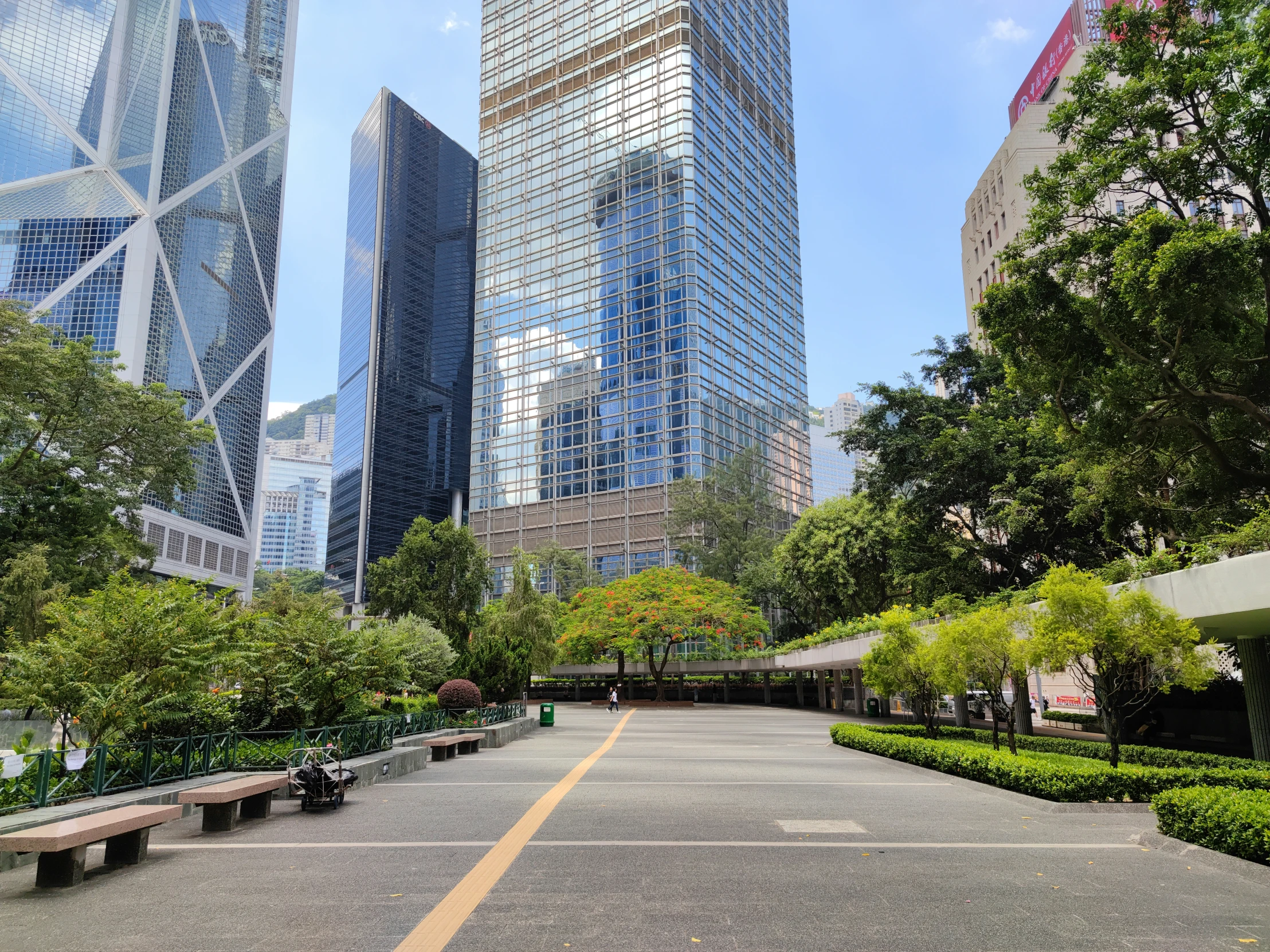 an empty park with benches and trees in front of a skyscr