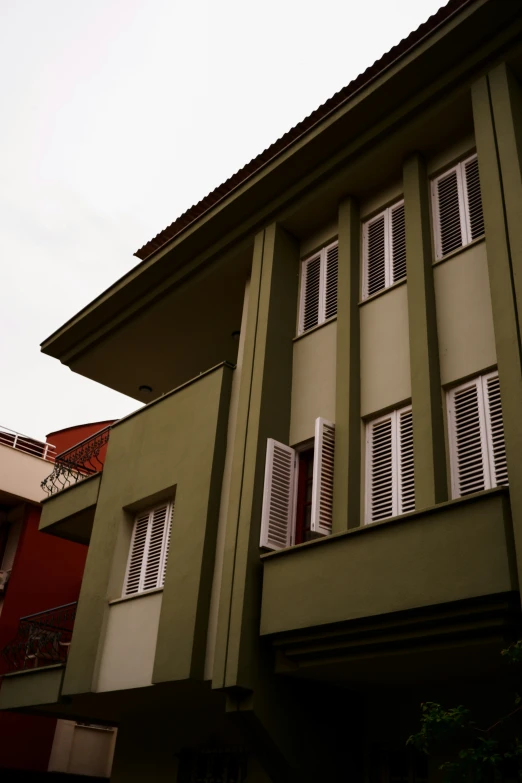 a green house with a balconies and shutters