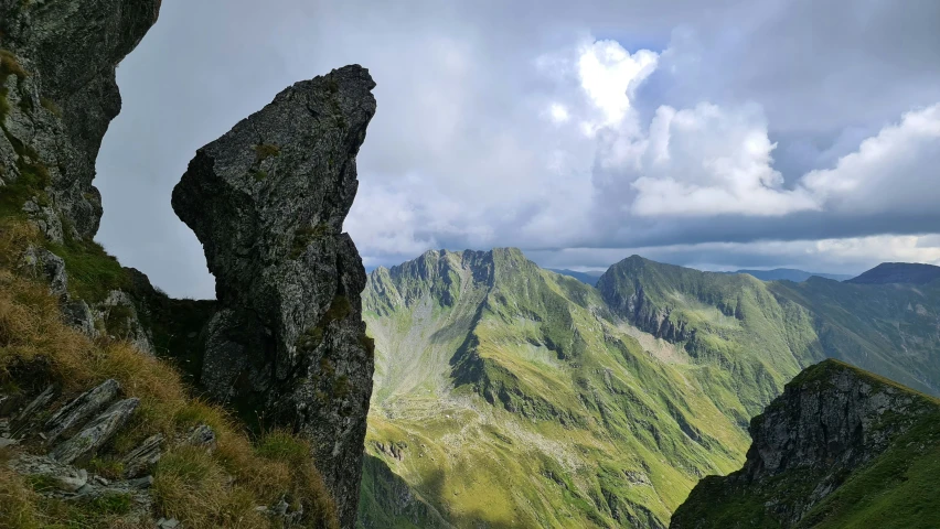 some rocks and grassy hills under a cloudy sky