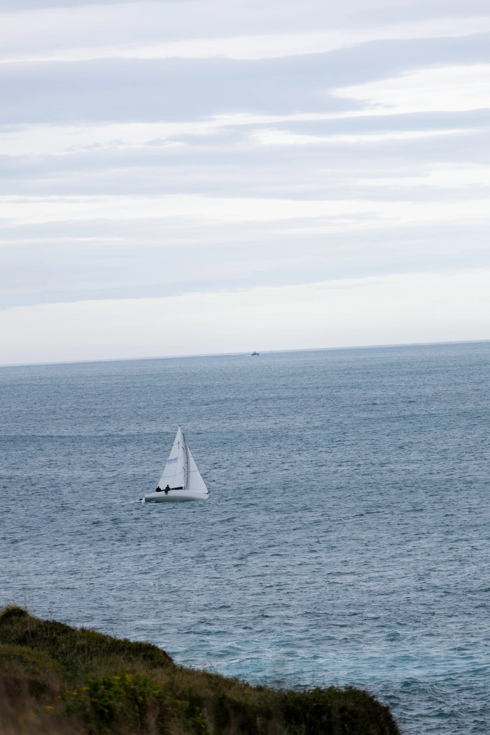 a white sailboat on the ocean with the sky in the background