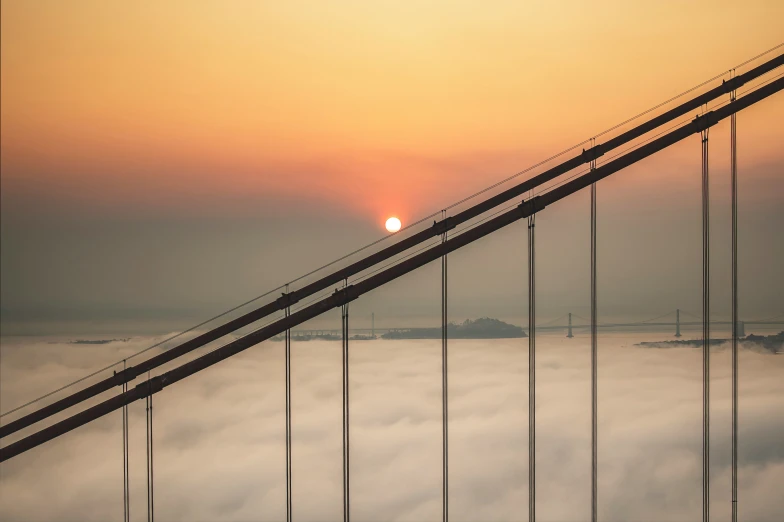the golden gate bridge during sunrise with low clouds