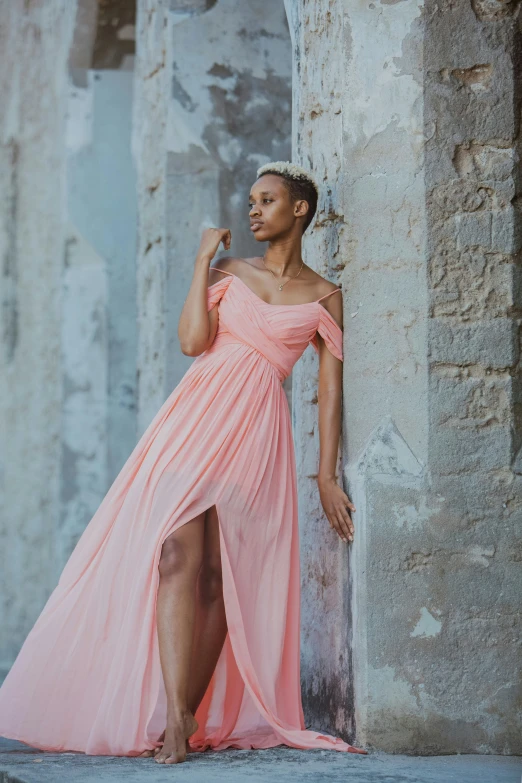 a woman standing in front of columns wearing a pink dress