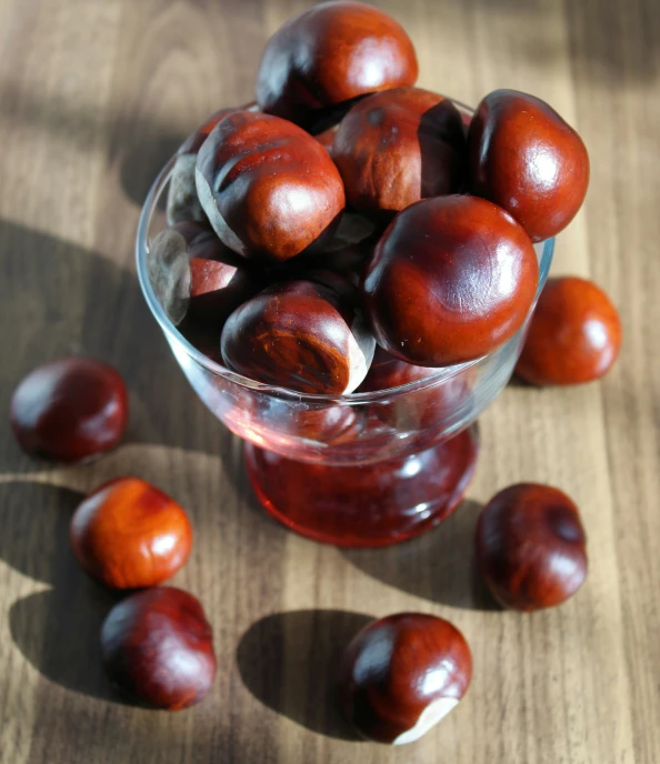 a glass filled with plums sitting on top of a table