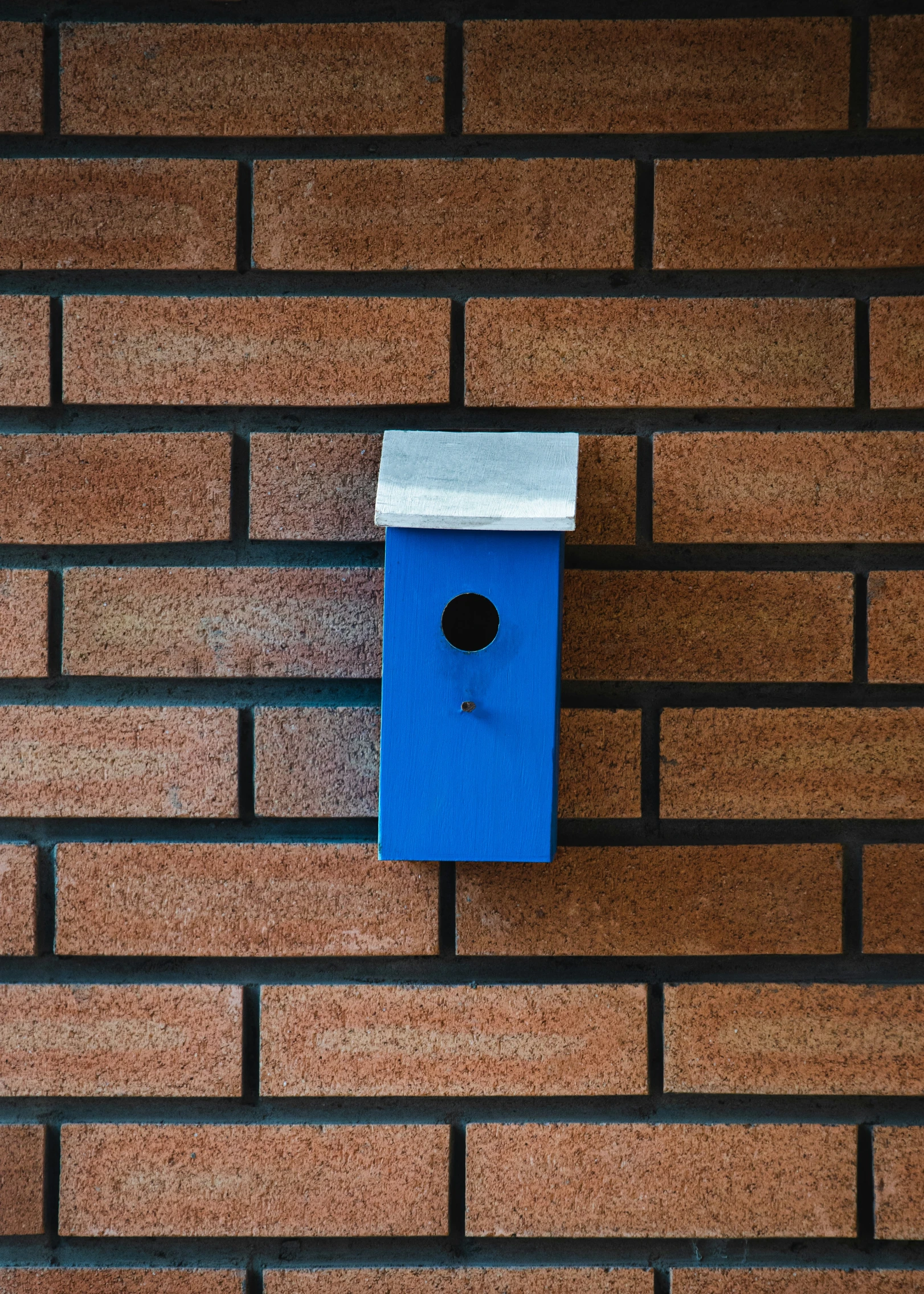 a small blue bird house sitting on top of a brick wall