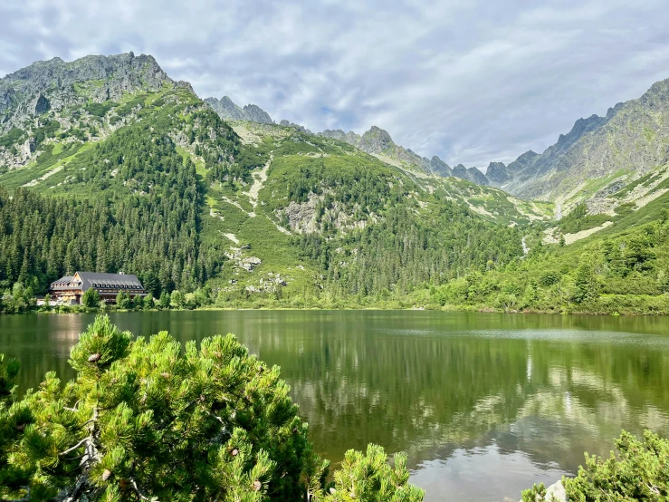 a lake surrounded by trees and mountain range in the background