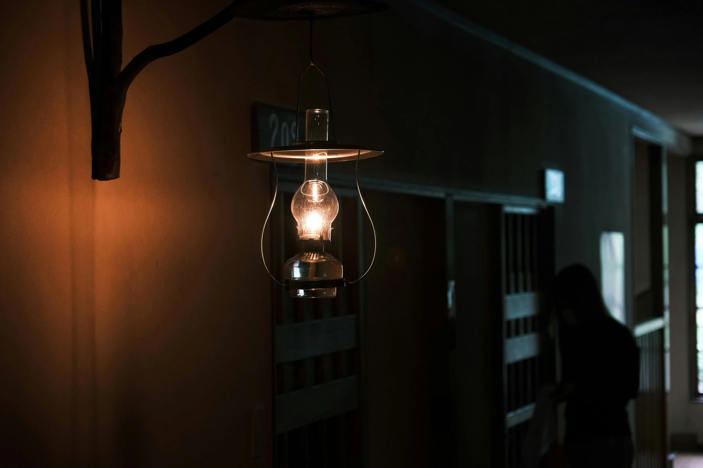 a person stands in the darkness near a light fixture