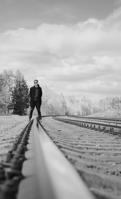 man on a skateboard standing at a train crossing