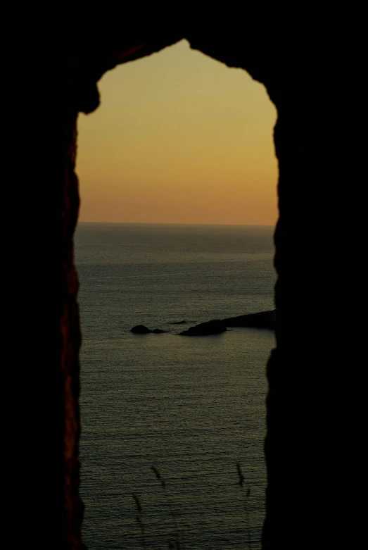 looking through a cave at an ocean at dusk