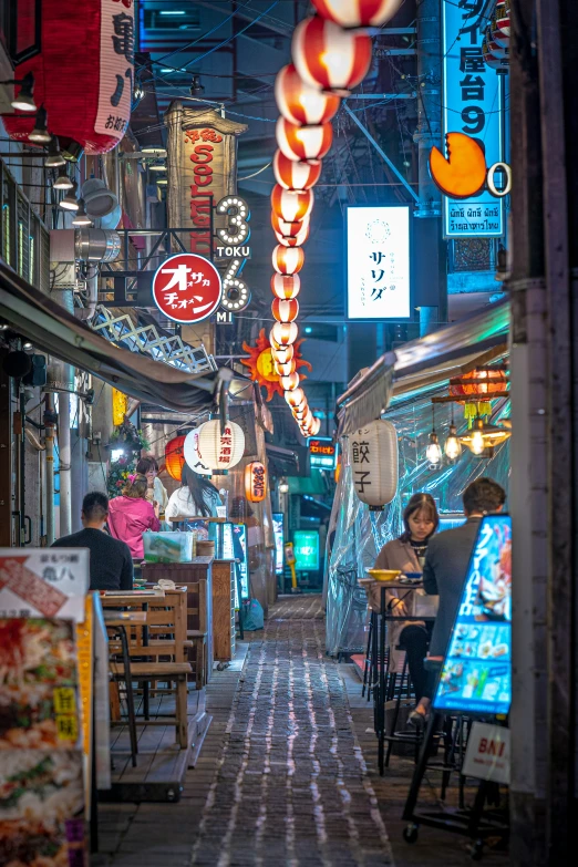 an asian street with lights on and a lot of food