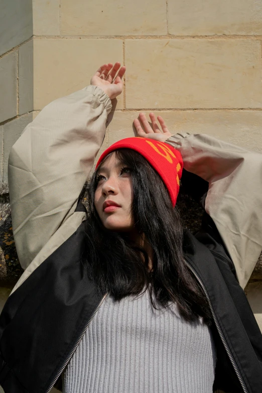 a woman in a jacket and red beanie is covering her head