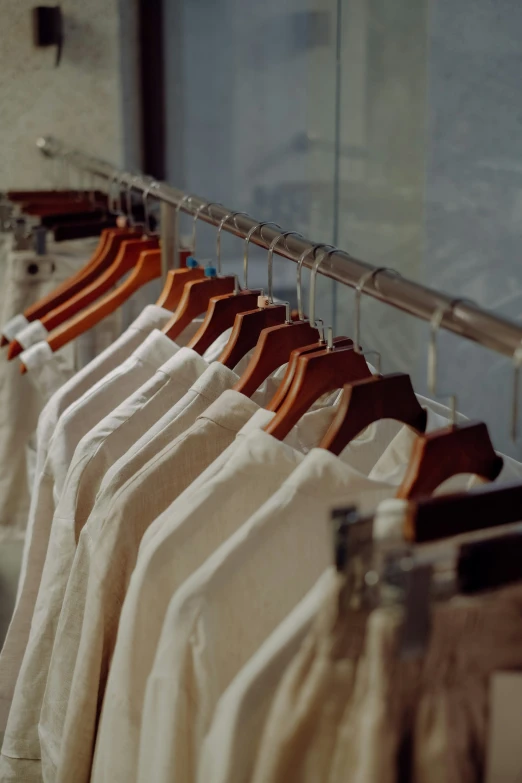 several white shirts hanging on a rack with their clothes folded