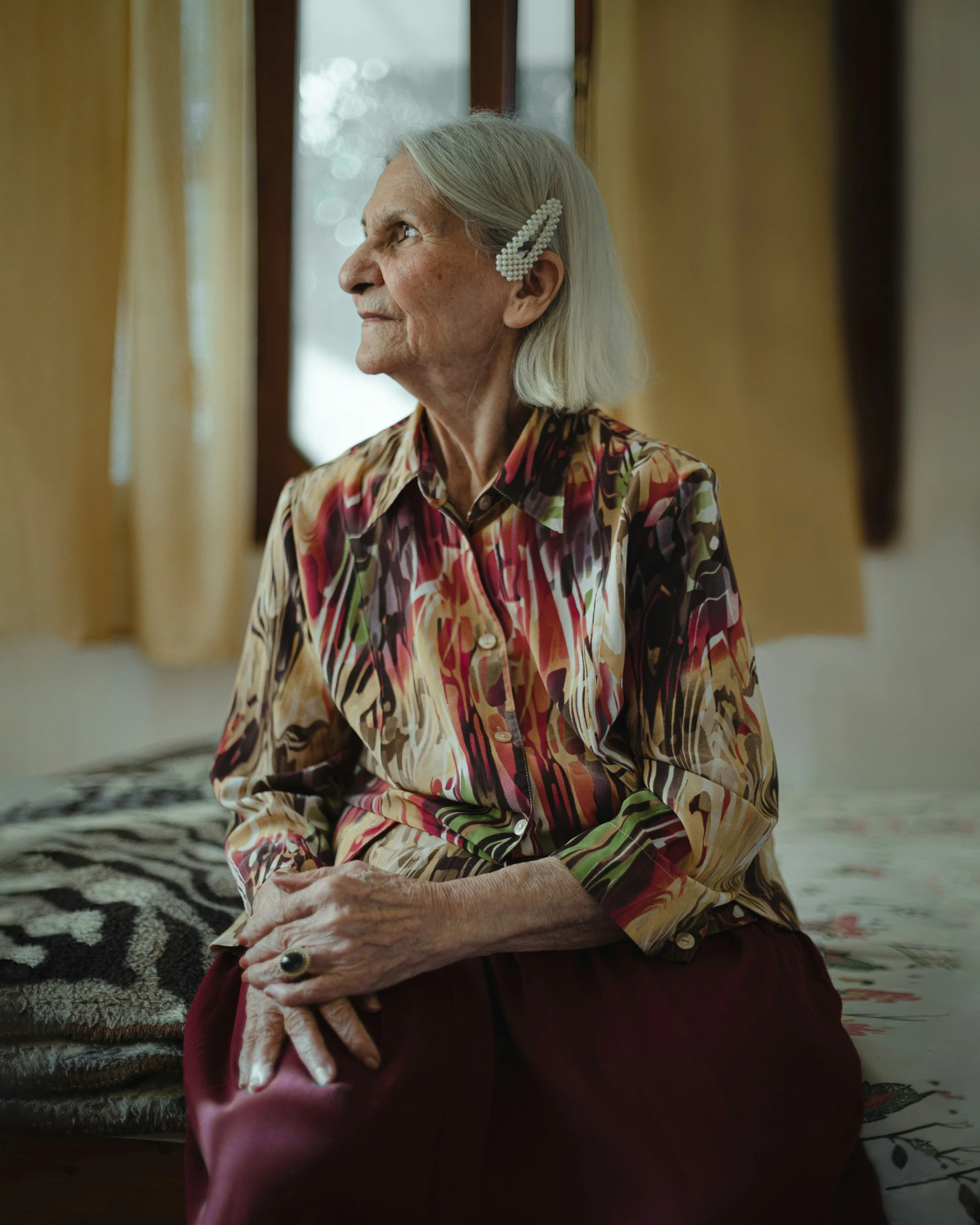 an old woman sits on a bed in her home