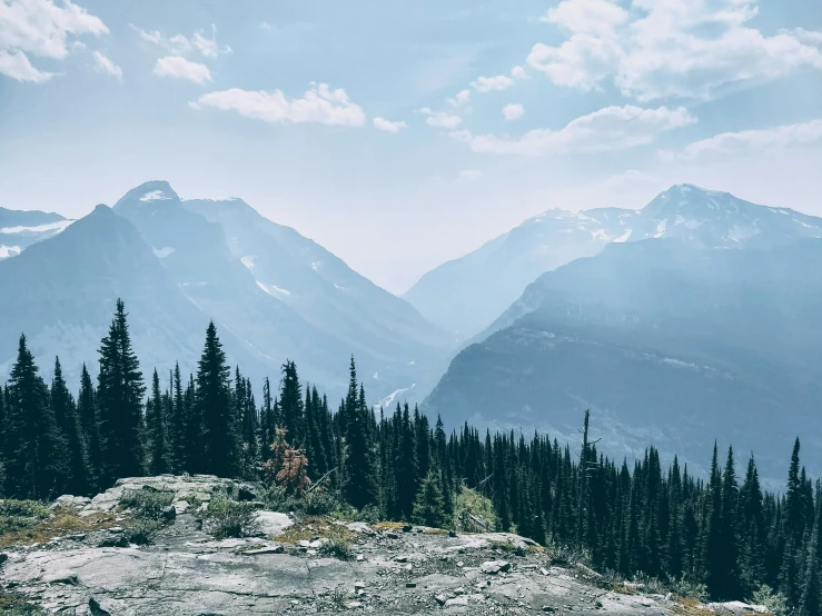 mountains and trees are featured against the cloudy sky