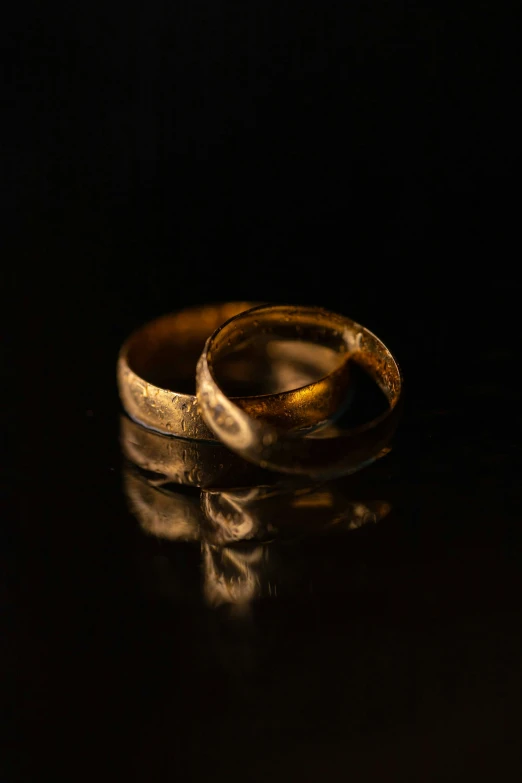 two gold wedding rings on top of a table