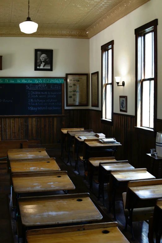 an empty classroom with tables and chairs by a chalkboard