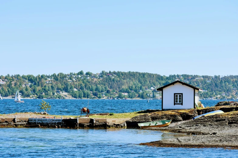 a tiny house next to the water surrounded by rocks