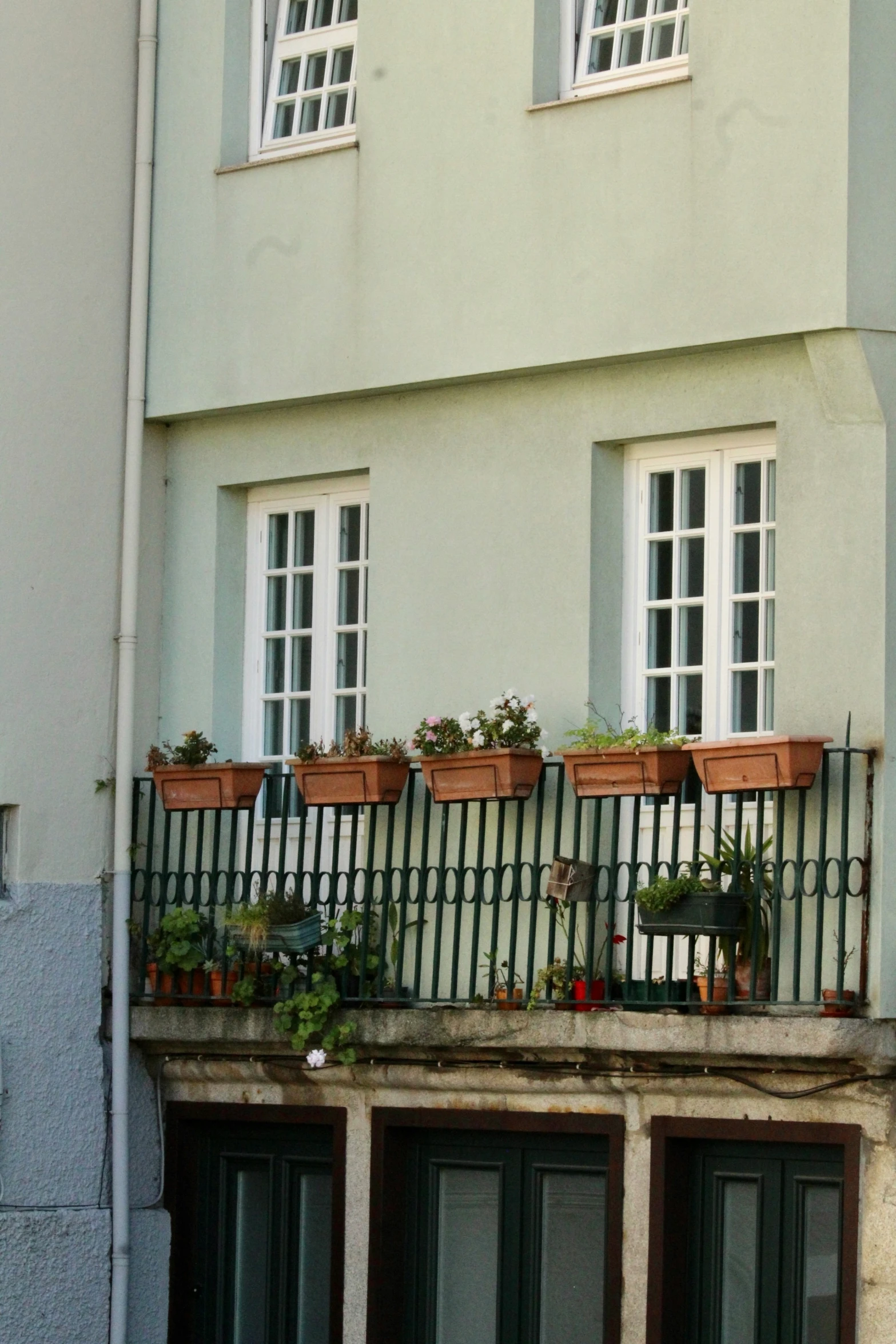 a balcony with several pots filled with plants and hanging potted plants