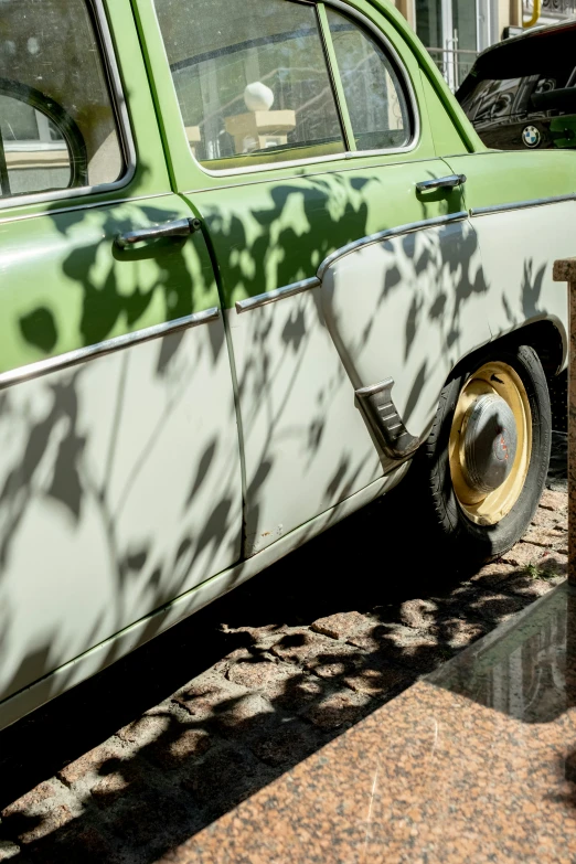 a car parked next to a wall near a tree