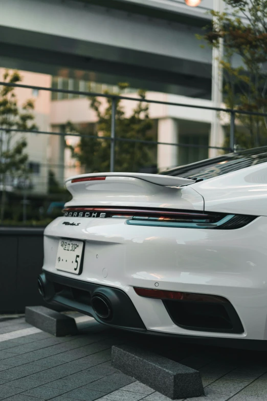 a white sports car parked on the sidewalk in front of a tall building