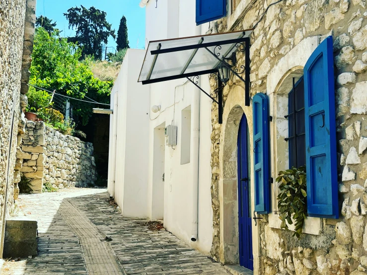 blue shutters lead to a white house on the cobblestone street