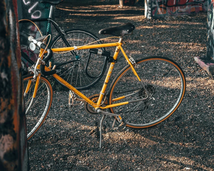 an old yellow bike is parked on the ground near graffiti