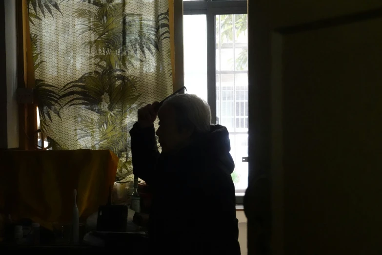 a woman standing in front of a window near curtains