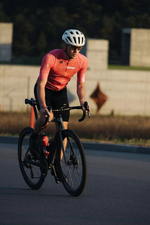 a man in a pink shirt rides a bike in the sun