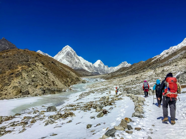 people in a group trekking uphill and down snowy mountains