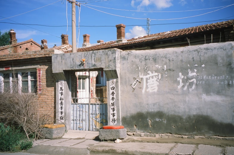 a wall of concrete next to a brick building with chinese writing on it