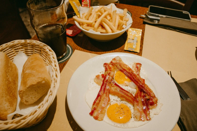 a plate with bacon and egg served next to french fries