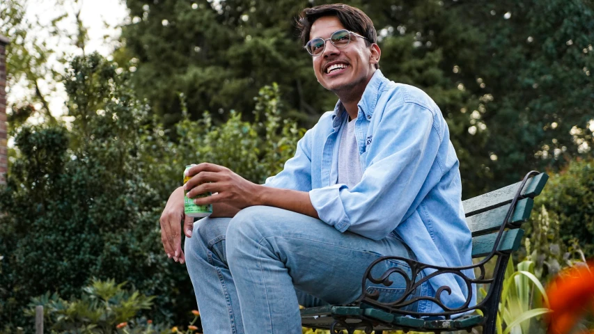 a man wearing glasses sitting on a bench in the park