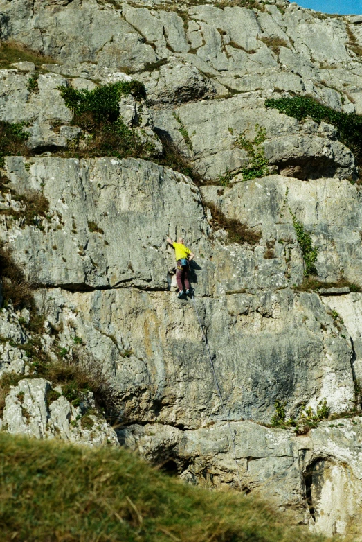 a person in yellow and black holding a surfboard sitting on top of a rock