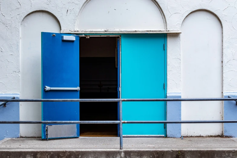 an open blue door stands out against a white stucco building