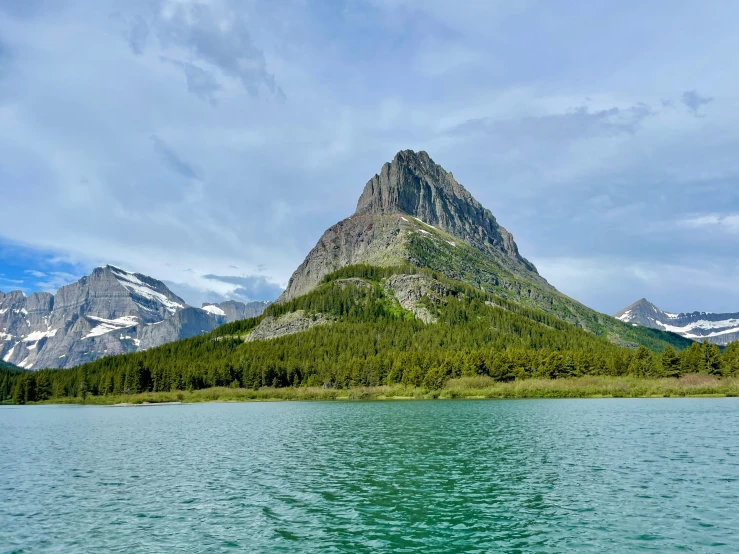 a mountain with mountains rising above it next to a lake